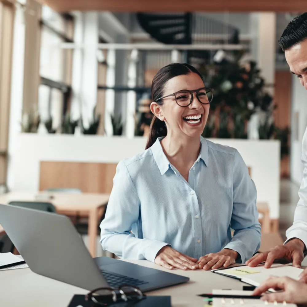 Bild von 3 Personen lachend am Schreibtisch